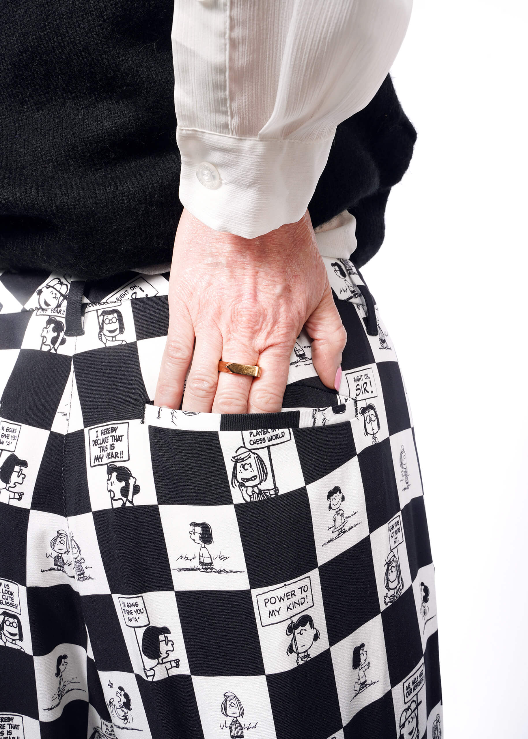 Close up of model's hand in back pocket of the checkered black and white Slim Crop Pant from the Peanuts x Wildfang collection. 