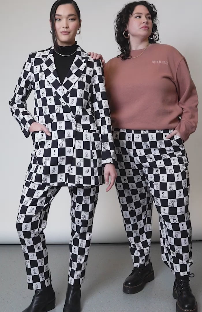 Video of two models in studio showcasing  the PEANUTS X WILDFANG slim crop pant. Shows close up of side and back pockets, bottom hem, belt loop, and printed fabric. 